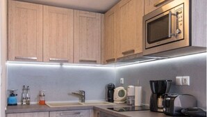 A compact kitchen with wooden cabinets, a built-in microwave, a coffee maker, and a dishwasher. - Virelian Studio, Divine Sea Views, Furnished Terrace, Naxos (Plaka)