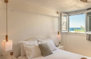 Ein Schlafzimmer mit einem Bett, Nachttischlampen, einem Fenster mit Blick und einer Wandleuchte.