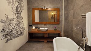 A bathroom with a freestanding bathtub, a wooden vanity with a white sink, and a large mirror above the vanity. - The Rockwall Boutique Hotel (Maha Induruwa)