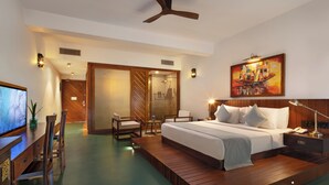A hotel room with a bed, a desk, a chair, a TV, and a painting on the wall. - The Rockwall Boutique Hotel (Maha Induruwa)