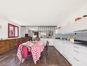 A modern kitchen with white cabinets, a red and white checkered table, and a herringbone floor pattern. - Family house for 8 – garden & BBQ (Longeville-sur-Mer)