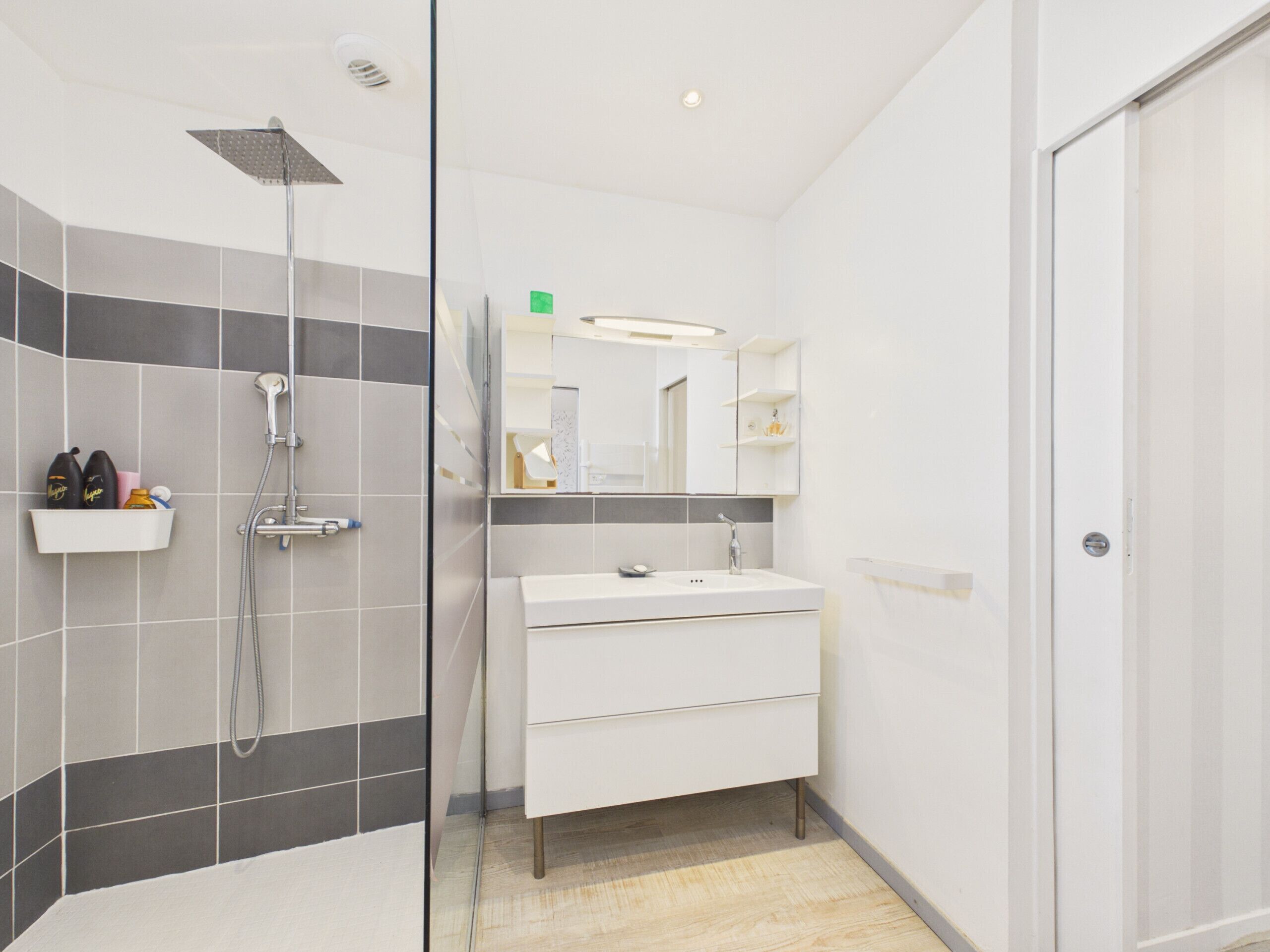 Ein modernes Badezimmer mit Dusche, Waschbecken und Spiegel.