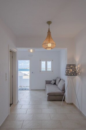 Ein Zimmer mit einer Couch, einer Stehlampe und Blick durch eine Tür.