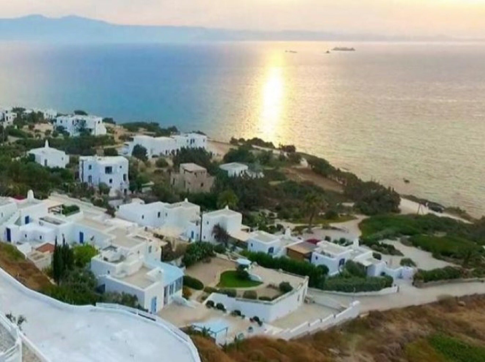 A coastal village with white buildings, a beach, and the sea.