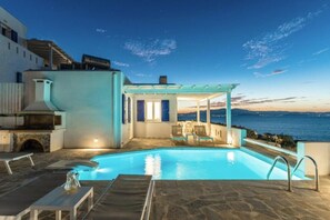 Ein Poolbereich mit überdachter Sitzgelegenheit, Steinböden und Blick aufs Meer.