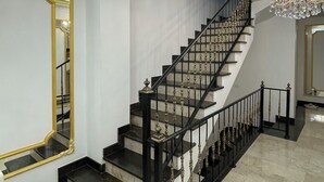 Una imponente escalera con barandales negros y un candelabro.