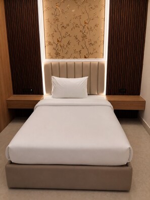 A bedroom with a bed, a headboard, a nightstand, and a wall with a floral pattern. - SERENEWOOD BY ZENVANA (Dehradun)