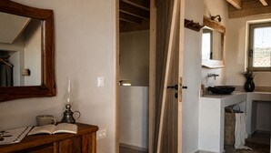 A room with a wooden dresser, a mirror, a reading lamp, and a door leading to another room. - Conte Maris Tower III - Sea View Mediterranean Escape (Tragaki)