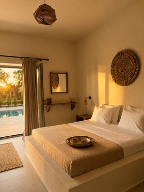 A bedroom with a large bed, a view of a swimming pool, and a circular wall decoration. - Conte Maris Tower III - Sea View Mediterranean Escape (Tragaki)