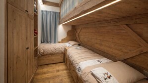 A narrow room with wooden walls and a sloped ceiling, featuring two beds with matching bedding and a small wardrobe. - Ca dei Nani - Exclusive Stay with Sauna (Cortina d'Ampezzo)