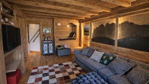 A cozy wooden interior with a sofa, a checkered rug, and a painting on the wall. - Ca dei Nani - Exclusive Stay with Sauna (Cortina d'Ampezzo)