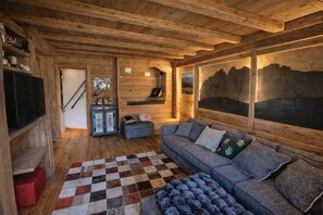 En ombonad träinredning med en soffa, en rutig matta och en tavla på väggen.