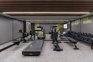 A gym with treadmills, weight machines, dumbbells, and a bench.