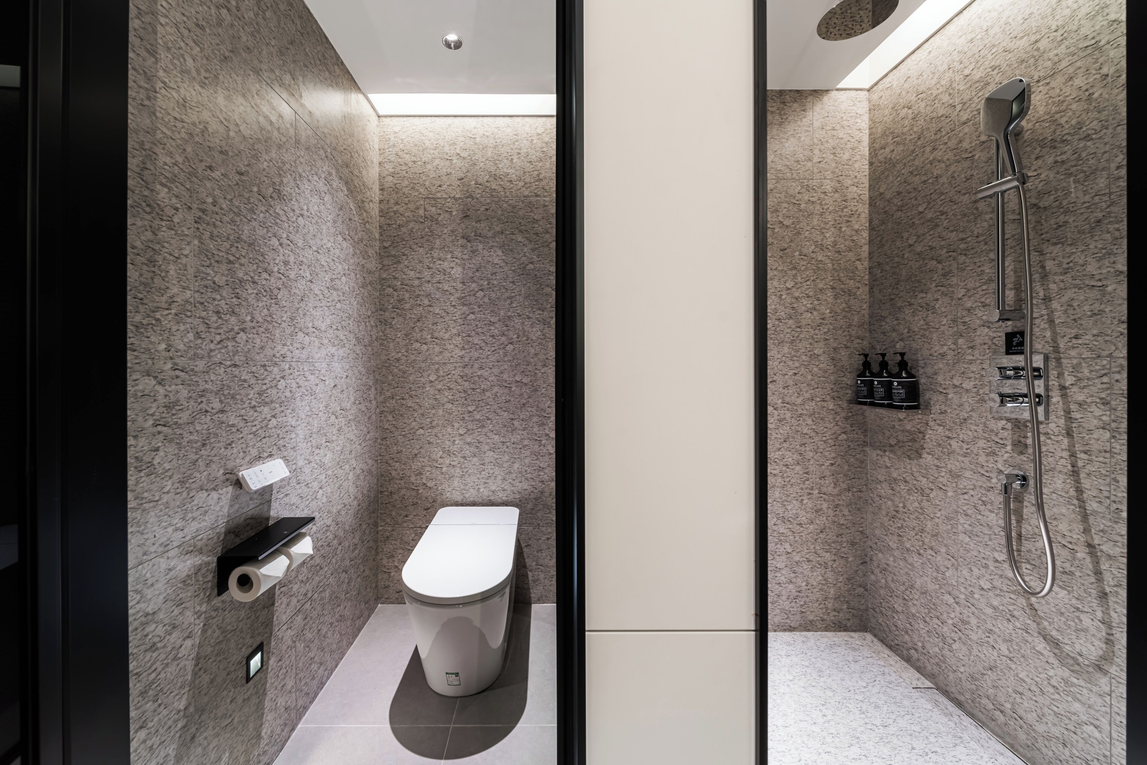 Une salle de bain moderne équipée de toilettes, d’une douche et d’un porte-serviettes.