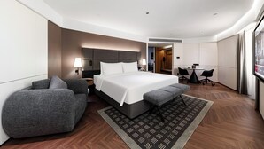 Una habitación de hotel moderna con una cama grande, un sofá, un escritorio y un televisor.