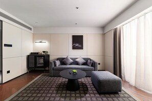 A modern living room with a sofa, ottoman, coffee table, and a small cabinet.