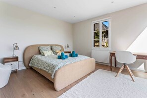 Une chambre à coucher avec un lit, des tables de chevet, un bureau et une chaise.