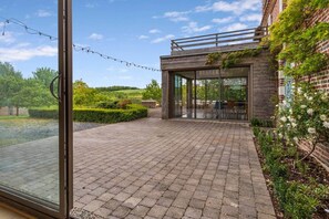 A patio area with a brick floor, outdoor seating, and a view of the countryside. - Stunning Norman Manor, 2 Hours from Paris (Léaupartie)