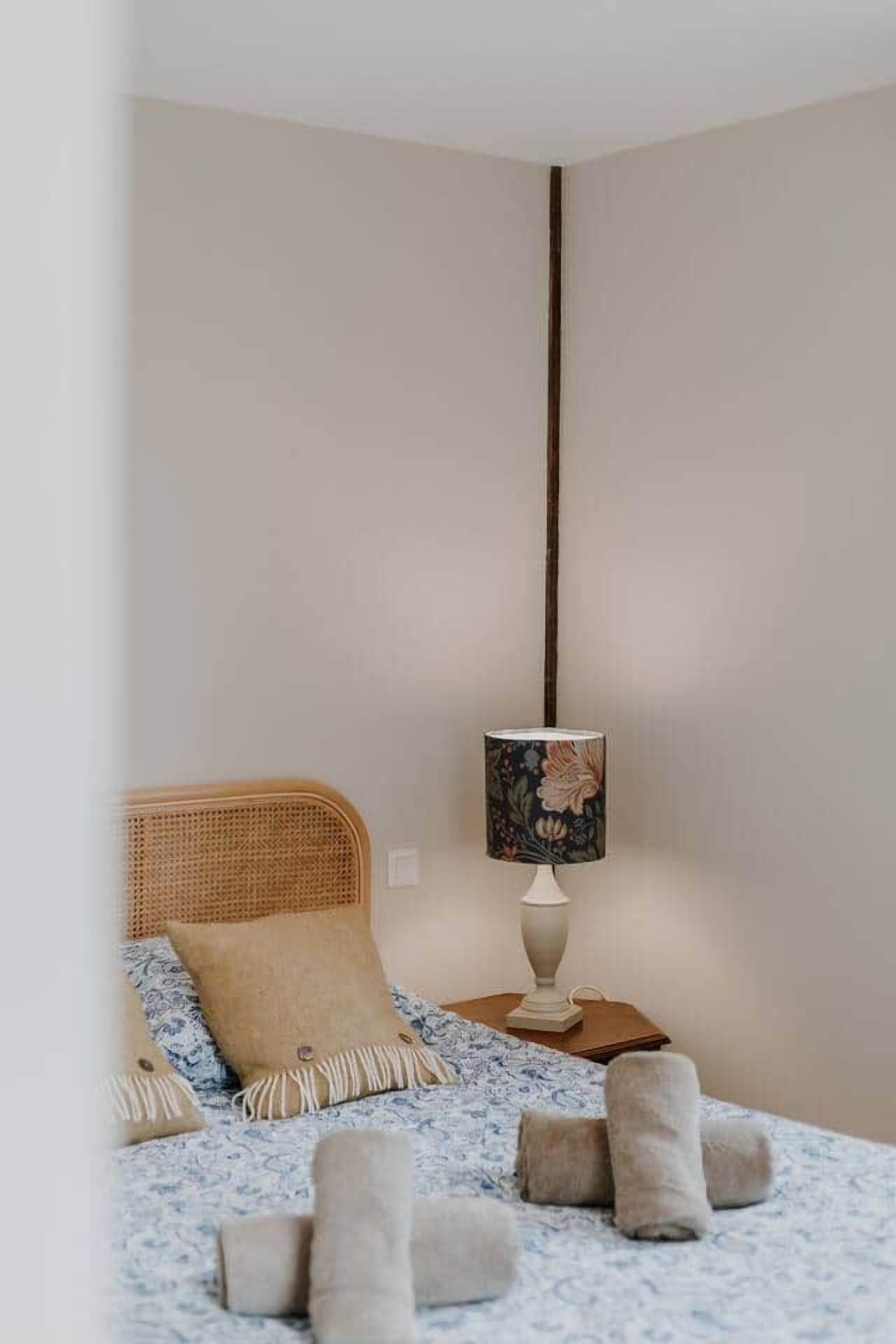 Un dormitorio con cama, una lámpara de noche y una luminaria de pared.