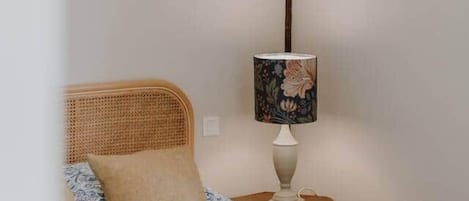 Un dormitorio con cama, una lámpara de noche y una luminaria de pared.