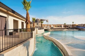 A swimming pool with a curved design, a palm tree, and a stage structure in the background. - Hurricane 3BR - Hot Tub & Mountain Views (Hurricane)