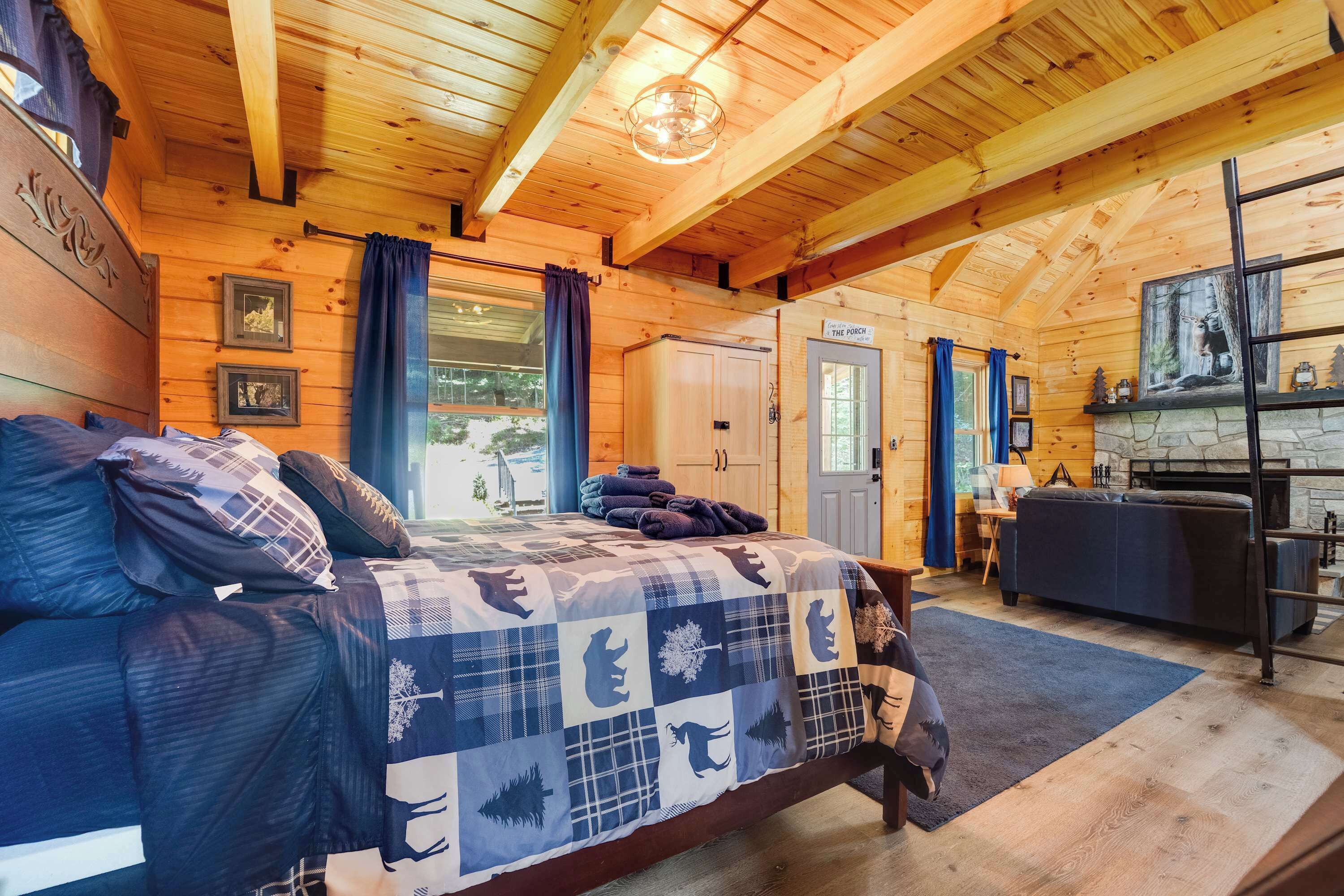 Interior de una cabaña de madera con cama, chimenea y comedor.