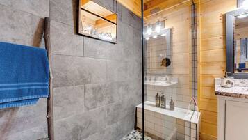 A bathroom with a wooden ceiling, a glass shower enclosure, and a tiled floor.