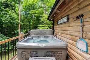 Un jacuzzi al aire libre frente a una cabaña de madera, con un letrero que dice 'BIENVENIDOS AL JACUZZI'.