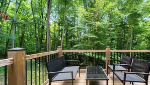 Terraza al aire libre con baranda de madera, rodeada de un bosque.