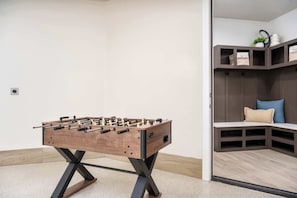Ein Tischkicker in einem Raum mit integrierter Sitzecke und Regalen.