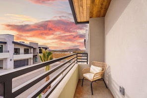Ein Balkon mit Blick auf Gebäude und einen Sonnenuntergang.