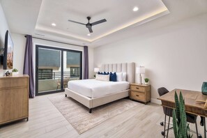 Ein modernes Schlafzimmer mit Bett, Nachttischen, einem Schreibtisch und einem Balkon.
