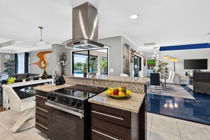 Una cocina moderna con una isla central, extractor de acero inoxidable y un cuenco de fruta.