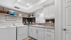 A modern kitchen with built-in appliances, a decorative backsplash, and a statement wall with a quote. - Private Pool + Spa + Outdoor Dining | Gulf Beaches | Blue Sunset (Bonita Springs)