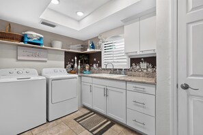 A modern kitchen with built-in appliances, a decorative backsplash, and a statement wall with a quote. - Private Pool + Spa + Outdoor Dining | Gulf Beaches | Blue Sunset (Bonita Springs)
