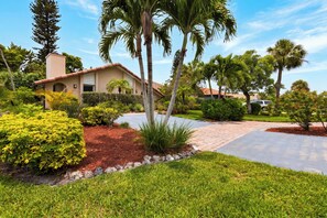 A residential property with a paved driveway, palm trees, and well-maintained landscaping. - Private Pool + Spa + Outdoor Dining | Gulf Beaches | Blue Sunset (Bonita Springs)