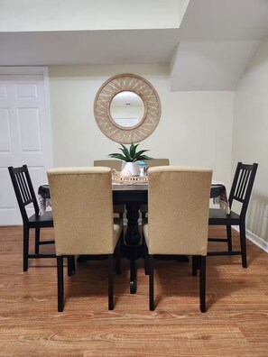 A dining area with a round table, four chairs, a mirror, and a potted plant. - Private, Terrace Level Apartment (Dacula)