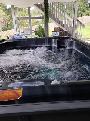 Ein Whirlpool mit Bedienfeld, umgeben von einer Holzdiele und einer überdachten Sitzgelegenheit.
