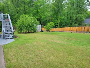 A backyard with a wooden deck, a small shed, and a fenced area. - Private, Terrace Level Apartment (Dacula)