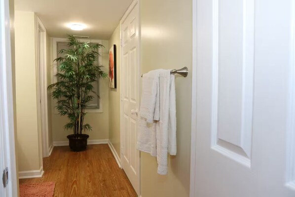 A hallway with a potted plant, white towels on a rack, and a door. - Private, Terrace Level Apartment (Dacula)