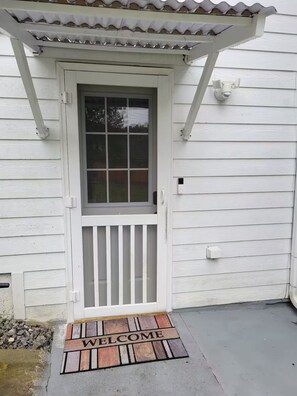 A white wooden house with a front door, a window, and a welcome mat. - Private, Terrace Level Apartment (Dacula)