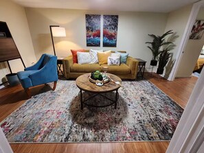 A living room with a sofa, a blue armchair, a coffee table, and a floor lamp. - Private, Terrace Level Apartment (Dacula)