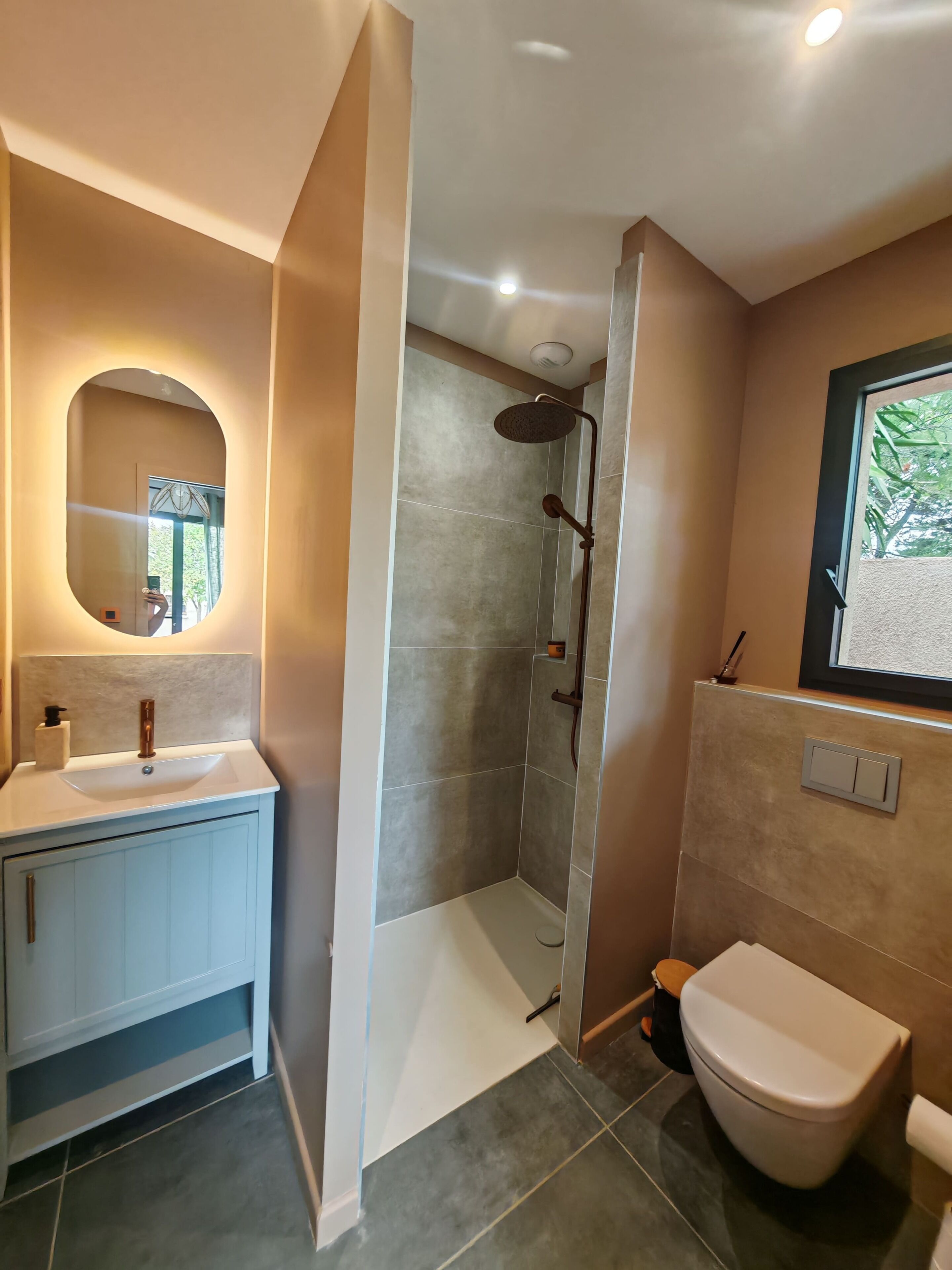 A bathroom with a shower, toilet, sink, and mirror.