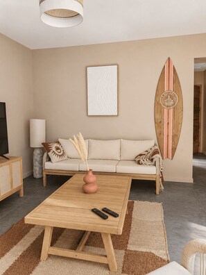 A modern living room with a sofa, a coffee table, a surfboard decoration, and a television. - Villa Mezzanotte in Le Brusc - 80 meters from the sea - Pool - Parking - Sleeps 8 - Cozy (Six-Fours-les-Plages)
