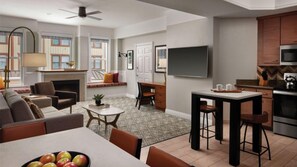 Een moderne woonkamer met een open haard, een eethoek met appels, een keuken met een magnetron, en een groot raam.