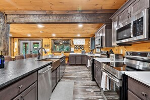 A modern kitchen with stainless steel appliances, wooden cabinetry, and a central island. - Sleeps 27 • Pool + Hot Tub + Theater + Near Pigeon Forge | It’s Got It All Y’all (Pigeon Forge)