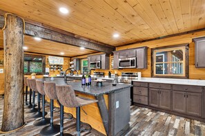 Een moderne keuken met een bar, houten plafond en barstoelen.
