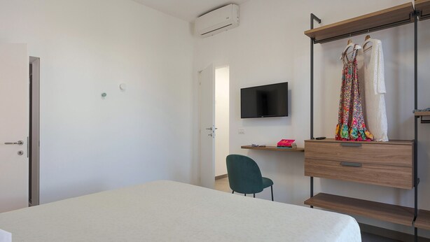 A bedroom with a bed, a desk, a chair, a TV, and a wardrobe. - Splendid sea-view villa in Marzamemi, Di Casa In Sicilia (Noto)