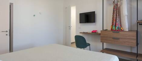 Un dormitorio con cama, escritorio, silla, televisor y armario.