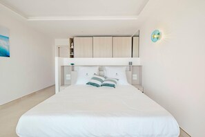 A modern bedroom with a large bed, built-in storage, and a wall-mounted light fixture. - New sea view Villa w/ private Pool and Jacuzzi - Sxm
Villa Noé (St Martin)